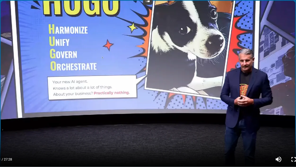 Comic-style slide from Malcolm Hawker's keynote: Hugo, a black-and-white terrier puppy, with the caption "Your new AI agent. Knows a lot about a lot of things. About your business? Practically nothing."